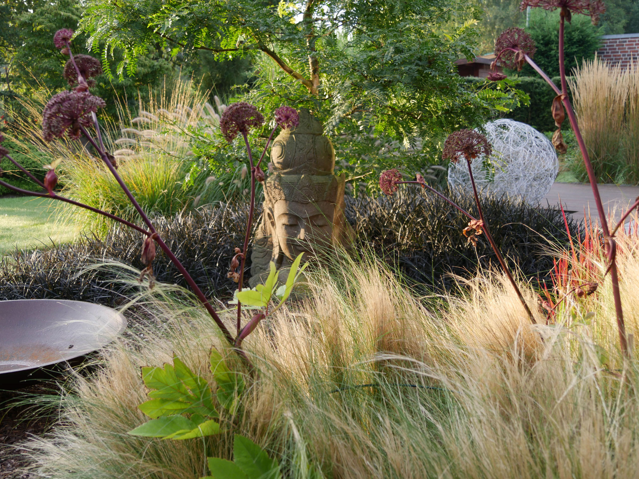 ein Gräserbeet mit Feuerschale in Terrassennähe